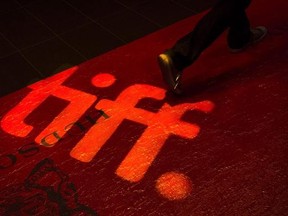 A man walks on a red carpet displaying a sign for the Toronto International Film Festival at the TIFF Bell Lightbox in Toronto on September 3, 2014. The Toronto International Film Festival says it remains committed to art-house and international cinema as it cuts two programs that featured such fare and reduces the overall number of titles it will screen for this year&#039;s edition by 20 per cent. THE CANADIAN PRESS/Darren Calabrese
