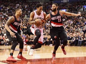 Toronto Raptors guard DeMar DeRozan (10) drives between Portland Trail Blazers guard Damian Lillard (0) and Trail Blazers guard Allen Crabbe (23) during second half NBA basketball action in Toronto on Sunday, February 26, 2017. THE CANADIAN PRESS/Frank Gunn