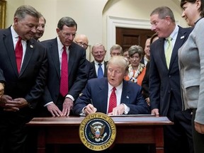 President Donald Trump signs the Waters of the United States (WOTUS) executive order, Tuesday, Feb. 28, 2017, in the Roosevelt Room in the White House in Washington, which directs the Environmental Protection Agency to withdraw the Waters of the United States (WOTUS) rule, which expands the number of waterways that are federally protected under the Clean Water Act. (AP Photo/Andrew Harnik)