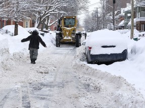 A snow grader navigates the narrow stretch of Third Avenue ,as a man is forced to walk on the street as sidewalks were uncleared, in Ottawa following a second snowstorm in less than a week. Wednesday February 15, 2017.