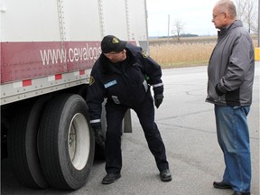 Chatham-Kent OPP Rob Enzlin talks to a truck driver who attended a wheel separation clinic held near Tilbury, Ont. in December 2015.