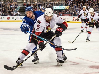 The Senators' Cody Ceci has company in the form of the Leafs' Leo Komarov as he heads for the corner.