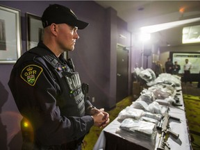 OPP Const. Roch Benoit stands beside seized weapons and drugs at a press conference in Vaughan, Ont. last week. Policing is a combination of education, judgment and maturity, writes the OPP commissioner.