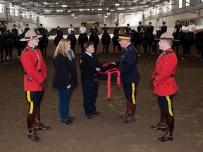 Bonnie Bishop of the Ontario SPCA receives a donated Musical Ride blanket from RCMP Supt. Mike Côté, Musical Ride & Heritage Branch at the Musical Ride stables.