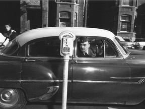 Serviceman Gerard Beaudoin looks out of his car at Ottawa's first parking meter, which was installed at the corner of Laurier and Metcalfe streets. April, 1958.