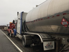 A tow truck hooks up a tanker trailer that lost a wheel Friday morning, striking five other vehicles.