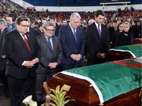 Prime Minister Justin Trudeau (right to left) Quebec Premier Philippe Couillard, Quebec City Mayor Regis Labeaume and Montreal Mayor Denis Coderre pay their respects by the caskets of the victims of the Quebec City mosque shooting at the Maurice Richard Arena in Montreal on Thursday.