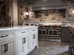 This kitchen features a stone backsplash, ironwork lighting and contrasting cabinetry.