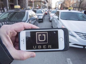 The Uber logo is seen in front of protesting taxi drivers at the Montreal courthouse, on February 2, 2016. Uber is crying foul over new tax measures announced in the federal government budget that would see the company subject to the same sales tax rules applied to taxi drivers.THE CANADIAN PRESS/Ryan Remiorz