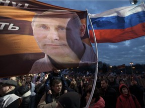 A flag with the portrait of Russian President Vladimir Putin waves over the crowd during the Vesna (Sping) festival commemorating the annexation, in Moscow, Russia, Saturday, March 18, 2017. Putin knows how to do propaganda.