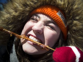 Alison Smithers of Toronto ignored the chill to completely enjoy the bacon cooked in maple taffy from Boivin Hastings Maple Products at the Great Canadian Maple Fest in Festival Plaza at Ottawa City Hall Saturday.