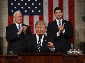 U.S. Vice President Mike Pence (L) and Speaker of the House Paul Ryan (R) applaud as U.S. President Donald Trump arrives to deliver his first address to a joint session of the U.S. Congress Tuesday night.