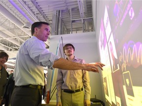 Minister of Finance Bill Morneau, left, touches an interactive display wall at Algonquin College before participating in a discussion on skills and innovation measures in Budget 2017 on Thursday.
