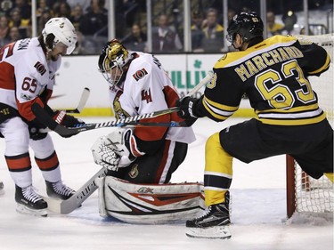 Bruins left-winger Brad Marchand (63) swats at the arm of Senators goalie Craig Anderson after he makes a save during the second period of Tuesday's game in Boston.