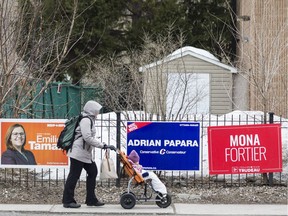 A pedestrian walks past candidate signs on Montreal Road. An Ottawa-Vanier by-election will be held Monday.