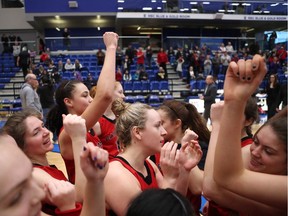 Carleton players celebrate the team's first national championship bronze medal following Sunday's 53-43 win over Queen's in Victoria.