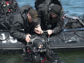 This file photo shows Royal Canadian Navy Clearance Divers assisting a diver as they prepare to get out of the water on May 19, 2015 during Operation OPEN SPIRIT, a multi-national underwater mine clearing exercise being held near Estonia, to rid the waters around the coast of mines that were laid during WWI and WWII. Photo: Cpl Chris Ringius.