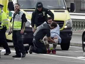 Emergency services staff provide medical attention to injured people close to the Houses of Parliament in London, Wednesday, March 22, 2017. London police say they are treating a gun and knife incident at Britain's Parliament "as a terrorist incident until we know otherwise." The Metropolitan Police says in a statement that the incident is ongoing. Officials say a man with a knife attacked a police officer at Parliament and was shot by officers. Nearby, witnesses say a vehicle struck several people on the Westminster Bridge.