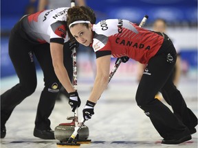 Joanne Courtney, right, looks over her shoulder as she and Emma Miskew sweep a stone thrown by Lisa Weagle during Canada's match against Russia on Sunday. The Canadians won 10-9 in an extra end. (Ju Huanzong/Xinhua via AP)