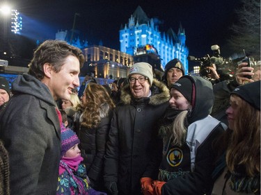 Prime Minister Justin Trudeau speaks to a volunteer at the Red Bull Crashed Ice World Championship at the Rideau Canal Locks, while Ottawa Mayor Jim Watson looks on, in Ottawa on Saturday, March 4, 2017.