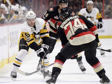 Pittsburgh Penguins' Josh Archibald (45) chips the puck past Ottawa Senators' Mark Borowiecki (74) during first period NHL hockey action in Ottawa, Thursday March 23, 2017.