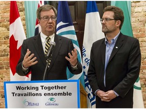 Ottawa Mayor Jim Watson and Gatineau Mayor Maxime Pedneaud-Jobin at Ottawa city hall – with a bilingual sign on the lecturn.