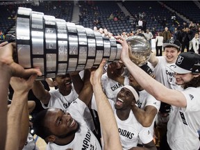Members of the Carleton Ravens men's basketball team raise the W.P McGee Trophy following their win over the Ryerson Rams in the USports basketball national championship game in Halifax on Sunday, March 12, 2017.