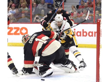 Pittsburgh Penguins' Tom Kuhnhackl (34) tries to get past Ottawa Senators' Chris Kelly (22) as the puck passes through Senators goaltender Mike Condon's (1) crease during first period NHL hockey action in Ottawa, Thursday March 23, 2017.