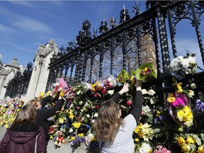People place flowers outside Britain's parliament in London on Saturday, March 25, 2017, for the victims of the Westminster attack on Wednesday.