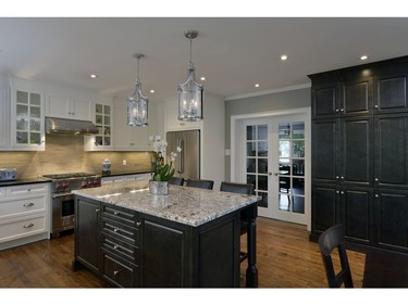 This large open concept kitchen features custom millwork, stone countertops and a beautiful backsplash.