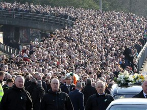 TOPSHOT - The coffin of former Northern Ireland Deputy First Minister Martin McGuinness is carried through the Bogside area of Derry, for burial at the City Cemetery of Derry on March 23, 2017.   Former Irish Republican Army commander turned peace negotiator Martin McGuinness divided opinion both in life and in death but on Thursday his supporters gave him the funeral of an Irish chieftain. /