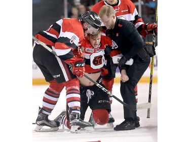 Travis Barron is helped up off the ice by Ryan Orban and  trainer Dan Marynowski after a fight in the second period as the Ottawa 67's take on the Mississauga Steelheads in game 4 of Ontario Hockey League playoff action at TD Place Arena.