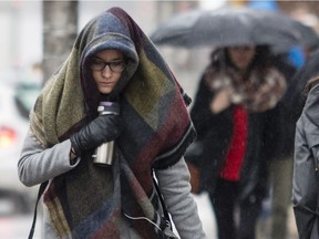 Women take cover from the rain along Laurier Avenue in Ottawa on Monday March 27,2017.