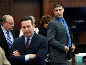 Defendant Aaron Hernandez, right, stands and looks as his attorneys confer during his double murder trial at Suffolk Superior Court, Tuesday, April 11, 2017, in Boston. Hernandez is on trial for the July 2012 killings of Daniel de Abreu and Safiro Furtado who he encountered in a Boston nightclub. The former New England Patriots NFL player is already serving a life sentence in the 2013 killing of semi-professional football player Odin Lloyd. (AP Photo/Elise Amendola, Pool)