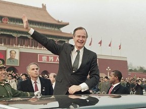 ADDS GEORGE H.W. BUSH TO NAME FILE - In this Feb. 25, 1989, file photo President George H.W. Bush stands on his car and waves to the crowds in Tiananman Square in Beijing. On the wall in the background is a huge portrait of Mao Zidong at the entrance to the Forbidden City. A president‚Äôs first 100 days can be a tire-squealing roar from the starting line, a triumph of style over substance, a taste of what‚Äôs to come or an ambitious plan of action that gets rudely interrupted by world events. (A