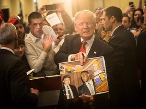 FILE - In this Jan. 29, 2016, file photo, Republican presidential candidate Donald Trump holds depictions of himself on, &ampquot;The Simpsons&ampquot; and a photo with boxer Mike Tyson, given to him by an attendee during a campaign stop at the Radisson Hotel in Nashua, N.H. &ampquot;The Simpsons&ampquot; released a short online clip on April 26, 2017, mocking President Donald Trump ahead of his 100th day in office. (AP Photo/John Minchillo, File)