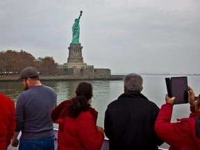 Visitors view the Statue of Liberty during a ferry ride to Liberty Island in New York on Nov. 5, 2015. New York&#039;s tourism industry is worried U.S. President Donald Trump&#039;s &ampquot;America First&ampquot; policies are turning off Canadian visitors, and they&#039;re heading north this week to woo Canucks and their tourism dollars. The head of New York City&#039;s official tourism organization, NYC & Company, minces no words in admitting he&#039;s keen &ampquot;to counter a little bit of the negative rhetoric that is coming out of Washi