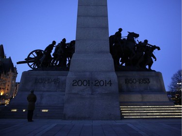 A man pauses in front of the National War Memorial after placing a candle.