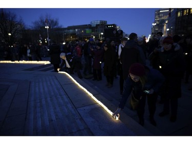 A woman places a candle at the National War Memorial.