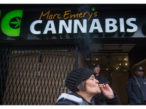 A woman smokes a joint as police officers stand outside the Cannabis Culture shop during a police raid, in Vancouver, B.C., on Thursday March 9, 2017. Jodie Emery, who says the Liberals' new pot legislation is prohibition 2.0, is one of the co-founders of the chain of dispensaries.