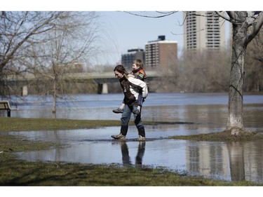 Alex Newman gets a piggy back from his mom Candace to cross a flooded section of Brighton Beach Park.