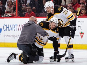 Colin Miller of the Boston Bruins is helped up by teammate John-Michael Liles and the team trainer after being injured in Game 1. Miller was listed as day-to-day by the Bruins on Thursday.