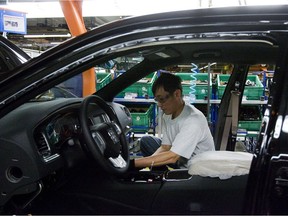 This File photo shows an auto worker on the assembly line at the Chrysler assembly plant in Brampton. Why do Ontarians pay such high insurance for their vehicles?