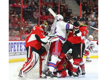 Craig Anderson of the Ottawa Senators tries to get his leg out of his net as Alex Burrows battles against Nick Holden.