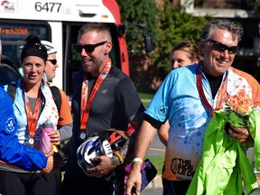 Alex Neron and his dad, Marcel, greeted by The Ottawa Hospital Foundation President Tim Kluke as they finish the 108 kilometre journey last year.