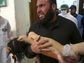 In this Tuesday April 4, 2017 file photo, provided by the Syrian anti-government activist group Edlib Media Center (and that is consistent with independent AP reporting), a man carries a child following a suspected chemical attack in the town of Khan Sheikhoun, Syria.