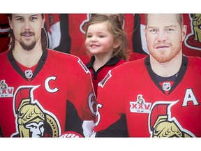 Four-year-old Kaitlyn Hennessey poses for a photo with the cardboard cutouts of Erik Karlsson and Chris Neil at the Canadian Tire Centre before the Ottawa Senators faced off to the Boston Bruins in Game 2.