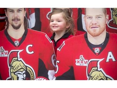 Four-year-old Kaitlyn Hennessey poses for a photo with the cardboard cutouts of Erik Karlsson and Chris Neil at the Canadian Tire Centre before the Ottawa Senators faced off to the Boston Bruins in Game 2.