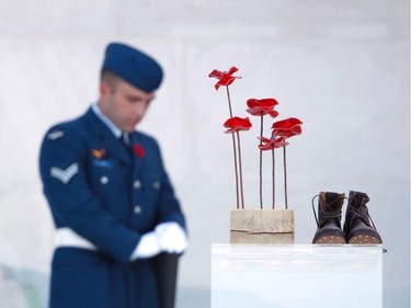 A soldier stands next to a sculpture of red poppies by artist Bernard Freseau and boots, dropped off the entrance of the Canadian National Vimy Memorial in Vimy, near Arras, northern France, on April 9, 2017, during a commemoration ceremony to mark the 100th anniversary of the Battle of Vimy Ridge, a World War I battle which was a costly victory for Canada, but one that helped shape the former British colony's national identity.  /