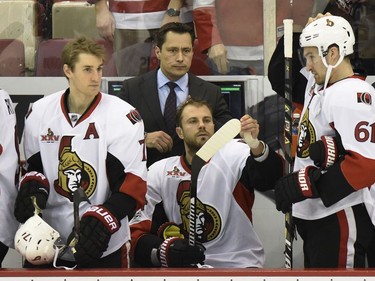 Ottawa Senators head coach Guy Boucher, center background, watches as his team prepares to play the Detroit Red Wings in the first period of an NHL hockey game, Monday, April 3, 2017, in Detroit.